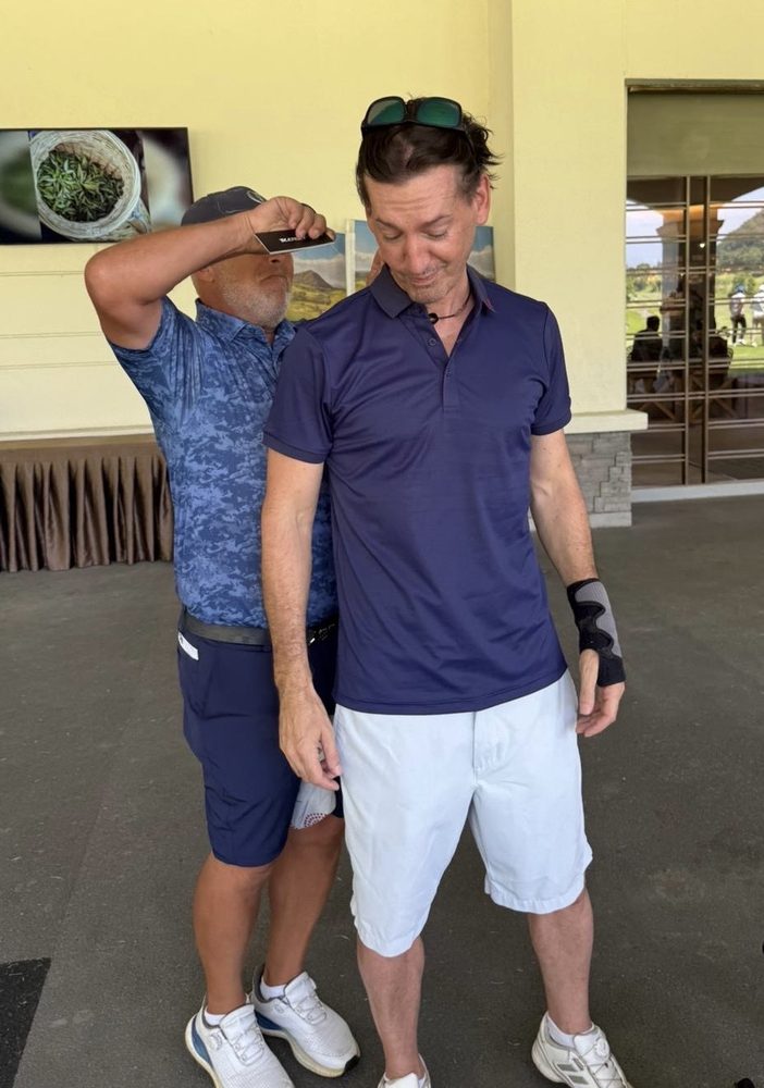 Two IGST members joking around by the clubhouse, one pretending to measure the other